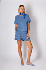 Stylish woman in blue cotton set with matching shorts and top, accessorized with a blue scarf.