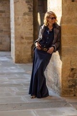Woman in elegant chemisier dress and blazer posing against stone wall, showcasing daily elegance with a touch of texture.