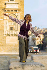 Woman wearing a stylish cashmere gilet and patterned blouse, walking confidently on a city street.