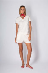 Model wearing a stylish cotton polo set, featuring a white top and matching shorts paired with red accessories.