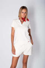 Model wearing a stylish white cotton polo set with red scarf, showcasing comfort for summer days.