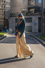 Stylish woman in oversized beige pants and a sweater, walking confidently on a city street, showcasing modern fashion.