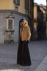 Woman in a stylish peacoat and cap, standing on a charming cobblestone street, exuding elegance and sophistication.