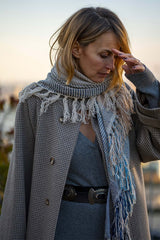 Woman wearing a stylish cashmere triangle scarf, paired with a checkered coat, showcasing elegance and luxury.