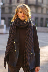 Woman in a stylish double-breasted velvet jacket and striped scarf, showcasing an elegant urban fashion look.