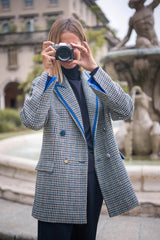 Fashionable woman in a stylish double-breasted checkered over jacket posing with a camera outdoors.