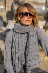 Elegant woman wearing a gray lace cashmere scarf, styled with sunglasses, exuding luxury and sophistication.