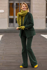 Smiling woman in green suit and yellow shoes, wearing a soft cashmere scarf, exuding elegance and style.