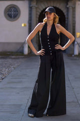 Model in a stylish black outfit with wide-leg pants and a fitted top, standing confidently outdoors.