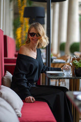Woman in a stylish black cashmere v-neck sweater sitting at a café, enjoying a drink.