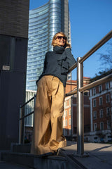Woman in oversized cashmere sweater and wide-leg trousers, enjoying a sunny day in an urban setting.