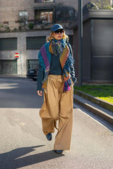 Woman wearing a colorful scarf and wide trousers, walking down a city street, showcasing a chic and stylish look.