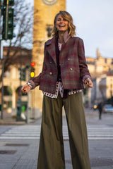 Woman wearing a stylish plaid peacoat with bold details, walking in an urban setting, showcasing modern elegance and individuality.