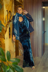Model showcasing a stylish cashmere tartan scarf paired with an elegant velvet dress in a modern lobby.