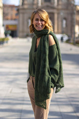 Smiling woman wearing a green cashmere sweater and a matching scarf in an outdoor setting.