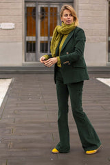 Woman in green corduroy suit with yellow shoes and scarf, showcasing a stylish and feminine look.