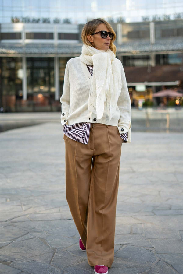 Woman wearing a white cashmere scarf with a cream cardigan and beige wide-leg pants, styled for modern elegance.
