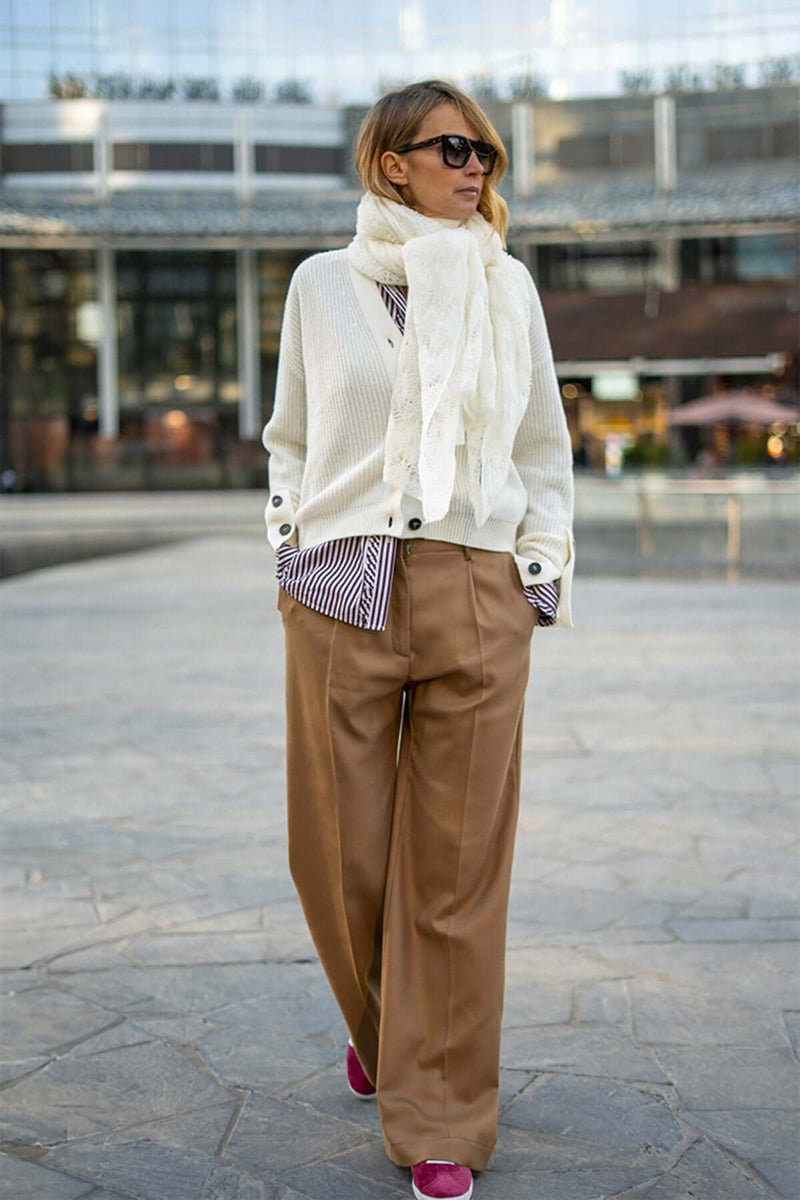 Woman wearing a white cashmere scarf with a cream cardigan and beige wide-leg pants, styled for modern elegance.