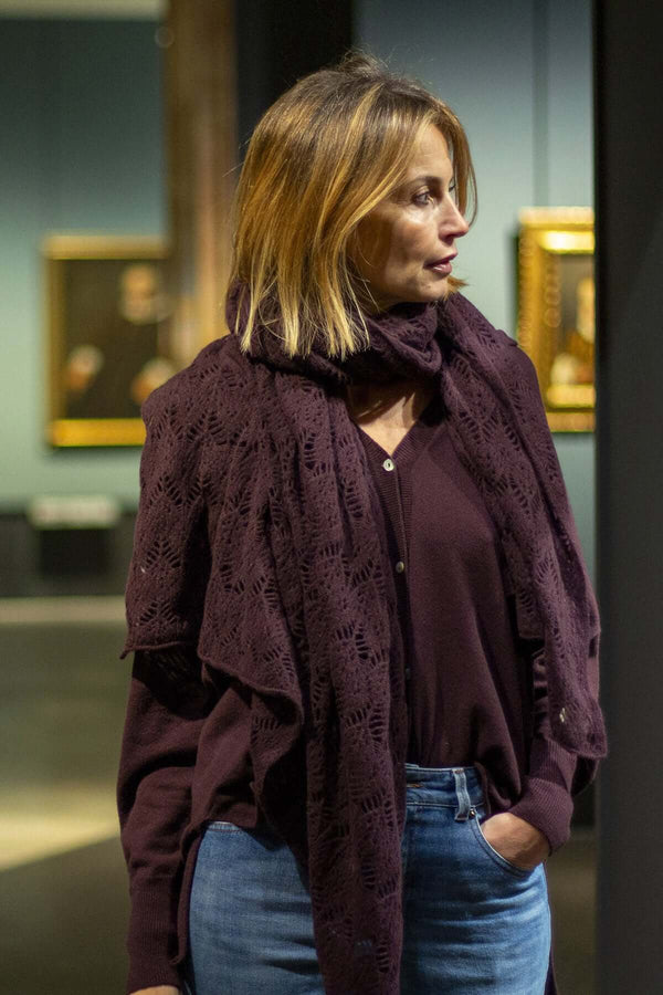 Woman wearing a dark purple sweater and scarf in an art gallery, showcasing a sophisticated casual look.